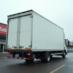 Camion de déménagement 20m3 avec hayon hydraulique abaissé dans un parking de grande surface