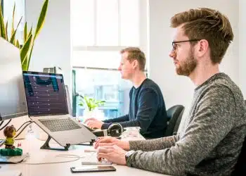 man sitting on chair wearing gray crew-neck long-sleeved shirt using Apple Magic Keyboard