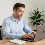 Homme comparant des devis d'assurance auto en ligne sur un ordinateur portable dans un bureau à domicile