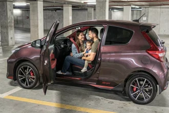 Famille urbaine installée dans une Toyota Yaris Sport rouge et noire dans un parking souterrain
