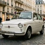 MINI Cooper diesel neuve blanche garée dans une rue parisienne pavée avec architecture haussmannienne en arrière-plan