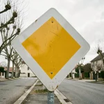 Panneau de priorité losange jaune et blanc sur poteau métallique en zone résidentielle française