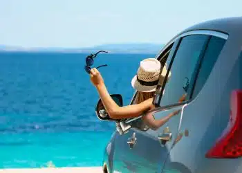 happy driver girl in hat and sunglasses in car at sea in summer