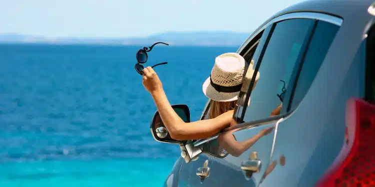 happy driver girl in hat and sunglasses in car at sea in summer