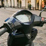 Tableau de bord numérique du Yamaha XMAX 125 affichant la vitesse au compteur, scooter garé en ville