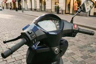 Tableau de bord numérique du Yamaha XMAX 125 affichant la vitesse au compteur, scooter garé en ville